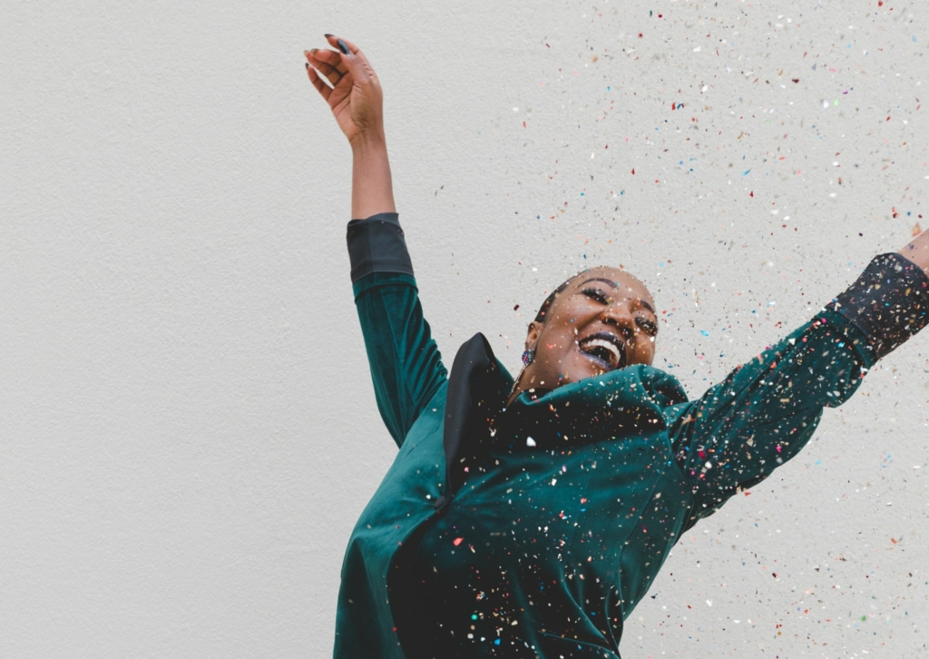 A woman smiling with confetti falling around her.